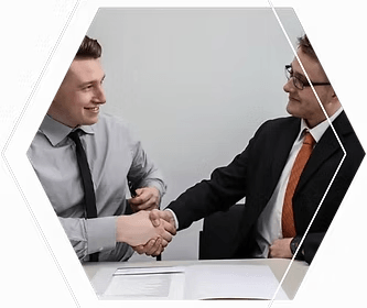 Two businessmen shaking hands at a table deal